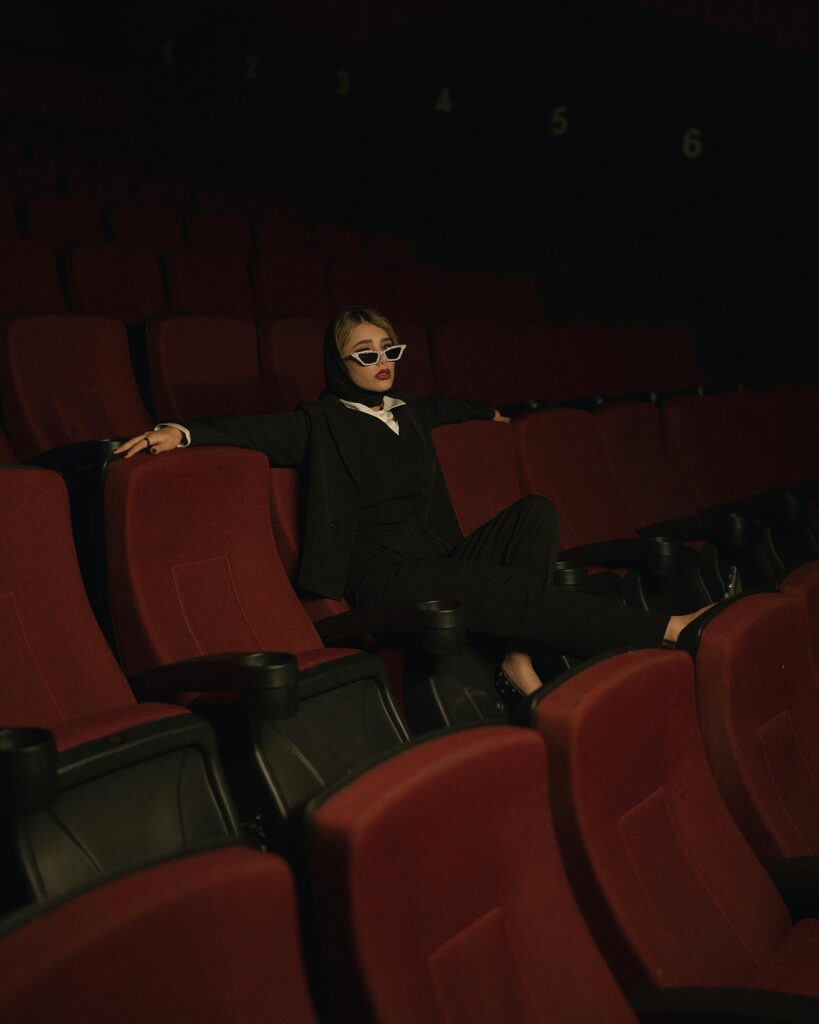 pexels-photo-25746374-25746374 Stylish woman in a black suit posing confidently in an empty movie theater.